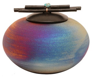 Pode incluir: Uma urna redonda de cerâmica com um esmalte azul, roxo e laranja. A tampa é de madeira e tem um acento de pedra turquesa.