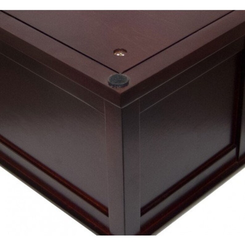 May include: A dark brown wooden box with a decorative trim around the edges. The box has a smooth, polished finish and features black felt pads on the bottom.