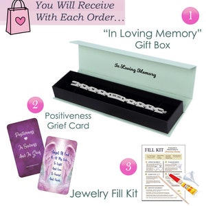 May include: A silver bracelet in a light blue gift box with the words "In Loving Memory" on the box. The bracelet is accompanied by a positivity grief card, a jewelry fill kit, and a shopping bag with a pink heart.