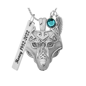 May include: Silver necklace with a wolf head pendant, a teal blue crystal, and a small wing charm. The necklace also includes a silver tag with the text "Honey 1982-2022".