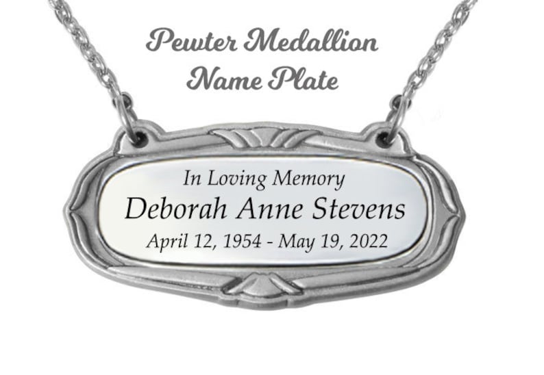 May include: A silver pewter medallion nameplate with the inscription "In Loving Memory Deborah Anne Stevens April 12, 1954 - May 19, 2022".