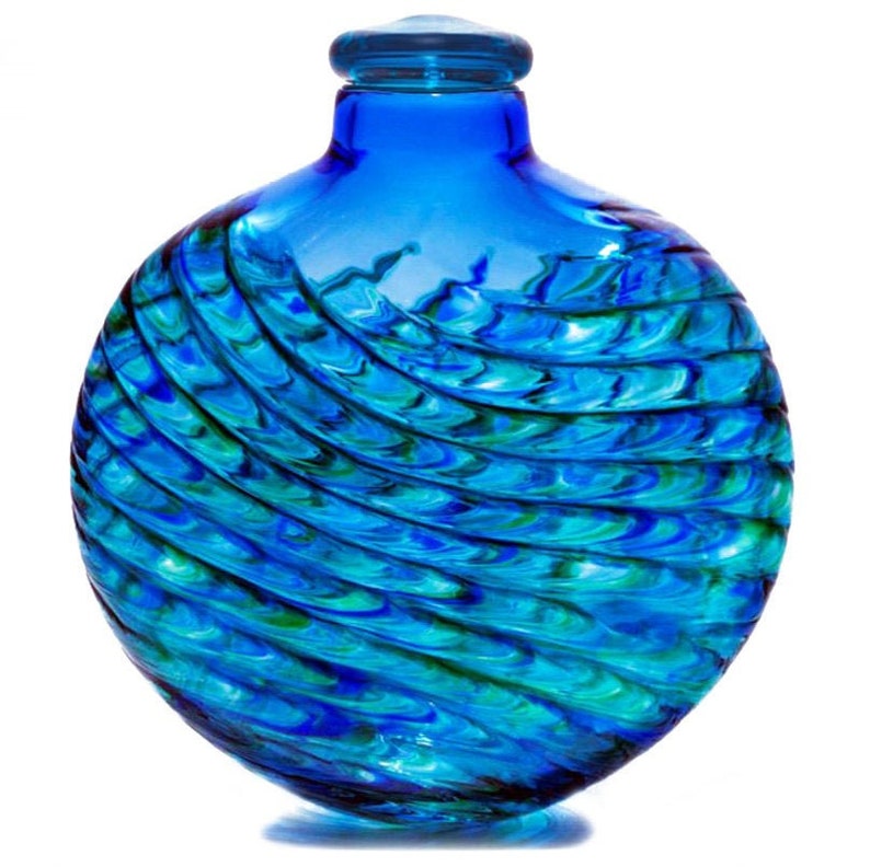 May include: A round blue glass bottle with a swirling green and blue pattern. The bottle has a clear glass stopper.