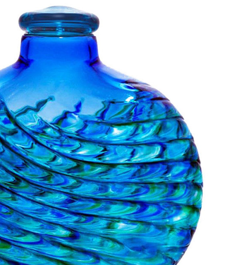 May include: A blue glass bottle with a swirling pattern of blue and green glass. The bottle has a round shape and a wide mouth.