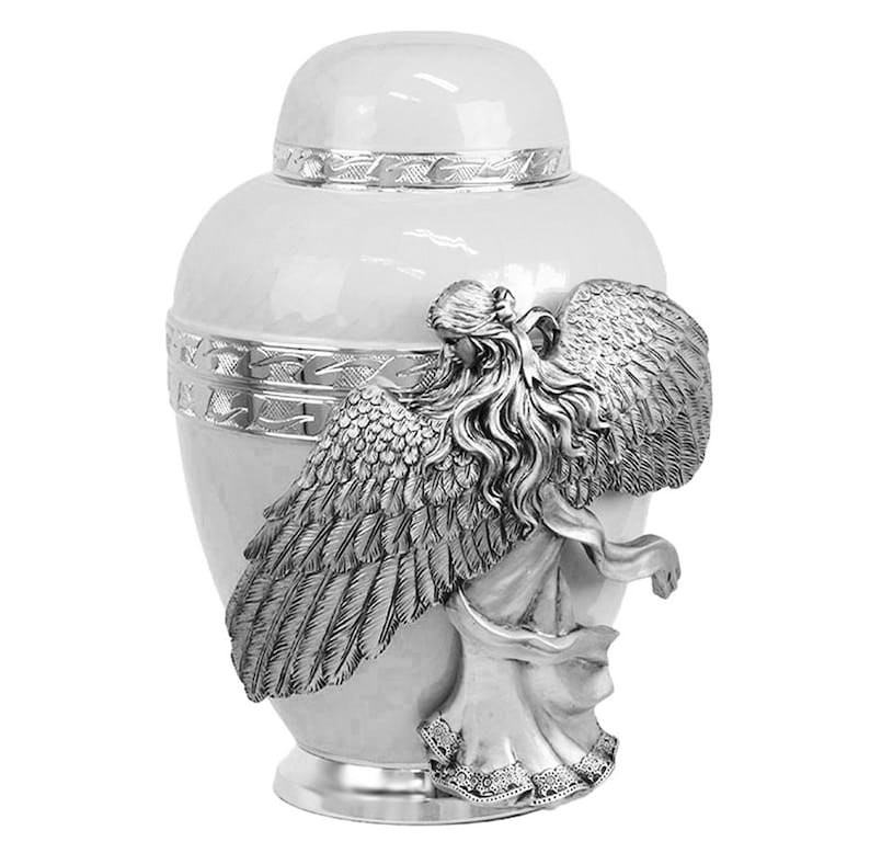 May include: White ceramic urn with a silver angel figurine on the side. The angel has wings and flowing hair.