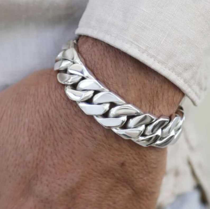 May include: A silver curb chain bracelet with large, chunky links.