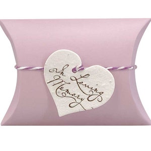 May include: A light purple pillow box with a white heart-shaped tag tied with twine. The tag has the words "In Loving Memory" written in brown ink.