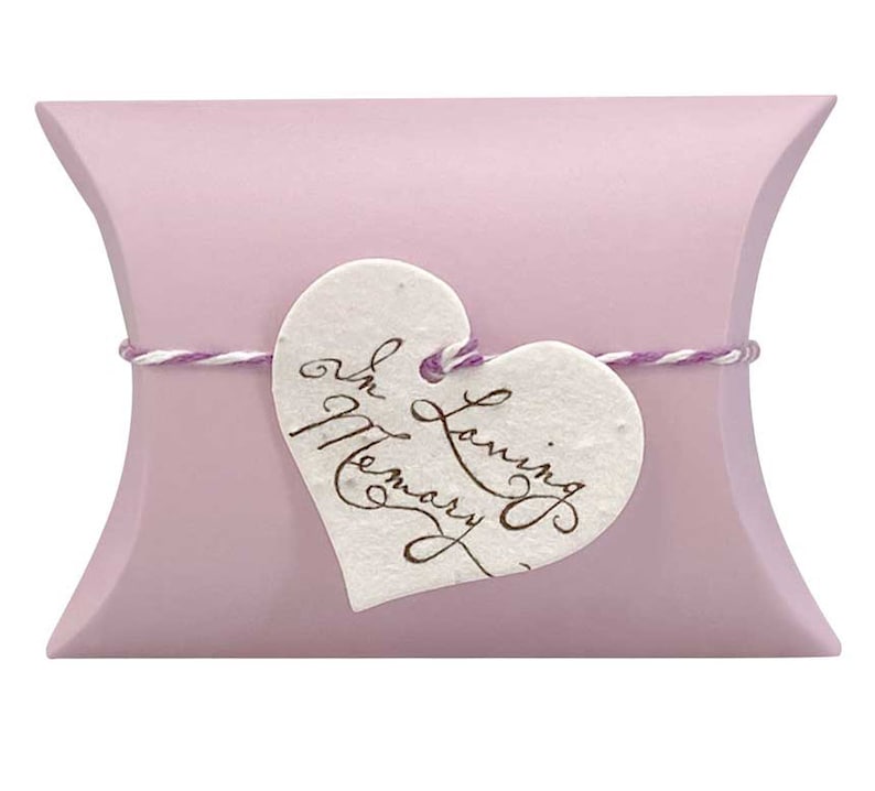 May include: A light purple pillow box with a white heart-shaped tag tied with twine. The tag has the words "In Loving Memory" written in brown ink.