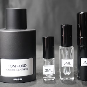 May include: Four bottles of perfume in different sizes. The largest bottle is black and says "TOM FORD OMBRE LEATHER PARFUM". The other bottles are smaller and say "3ML", "5ML", and "8ML".
