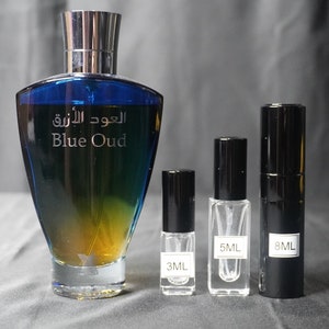 May include: A blue and gold glass bottle of Blue Oud perfume with a silver cap. Three smaller bottles of perfume are in front of the larger bottle. The smaller bottles are labeled 3 ml, 5 ml, and 8 ml.