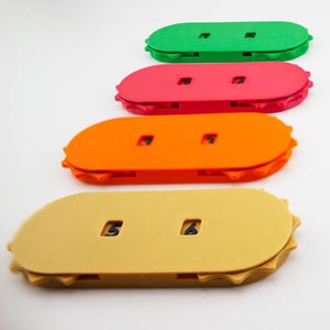 Könnte beinhalten: Eine Sammlung farbenfroher, ovaler Flaschenöffner in verschiedenen Farben, darunter Grün, Pink, Orange und Blau. Einige Öffner haben Zahlen aufgedruckt.