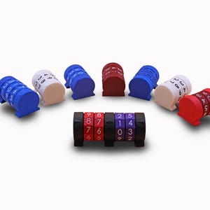 Op de afbeelding: Een verzameling van acht kleine, cilindrische nummertellers gerangschikt in een halve cirkel met één zwarte teller op de voorgrond. Elke teller is voorzien van draaiende wielen met witte cijfers. De kleuren zijn blauw, wit, rood en zwart, waarbij de voorste teller de cijfers 8, 7, 6, 2, 5, 1, 4, 0, 3, 2 weergeeft.