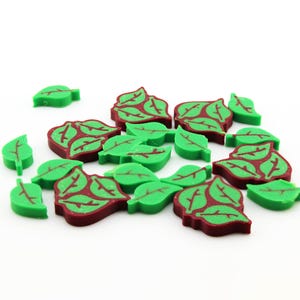 Könnte beinhalten: Eine Sammlung von grünen und kastanienbraunen Blattschmuck. Die Blätter haben ein detailliertes Adernmuster und sind auf einem weißen Hintergrund verstreut. Diese dekorativen Elemente könnten für Bastelarbeiten oder Scrapbooking verwendet werden.