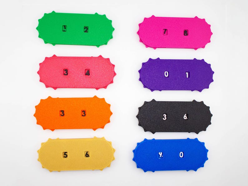May include: Eight colorful, rectangular number cards with scalloped edges. Each card displays a different number combination in white. Colors include green, pink, red, purple, orange, black, yellow, and blue. The numbers are clearly printed.