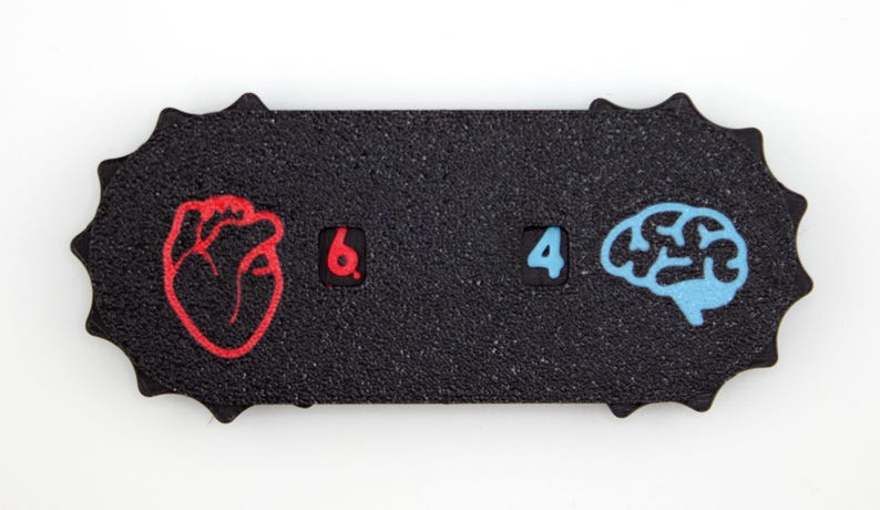 May include: A black, textured, rectangular object with a unique, starburst-like edge. It features a red heart graphic, the number 6, the number 4, and a blue brain graphic. The design is simple and graphic.