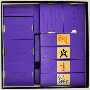 May include: A purple board game box with various compartments and card decks. The box is filled with purple components, including card holders labeled "Elemental Demons," "Drow Dragons," and "Aberration Undead." The card decks are labeled "House Guard," "Priestess of Lolth," and "Starting Deck."