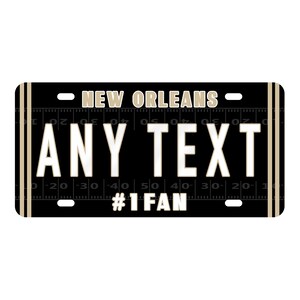 Puede incluir: Placa de matr&iacute;cula negra y dorada de Nueva Orleans con el texto "ANY TEXT" y "#1 FAN".