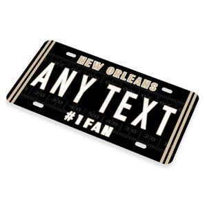Puede incluir: Placa de matr&iacute;cula negra y dorada de Nueva Orleans con el texto "ANY TEXT #1FAN".