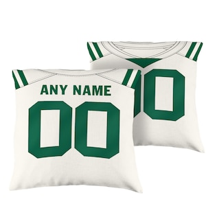 Puede incluir: Dos fundas de almohada blancas con rayas verdes y blancas en los hombros. Una funda de almohada tiene el texto "ANY NAME" y el número "00" en verde. La otra funda de almohada tiene el número "0" en verde.