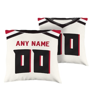 May include: Two white throw pillows with black and red trim. The pillows feature a black and red jersey design with a number "00" and the text "ANY NAME".