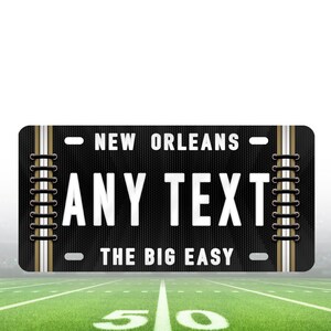 Puede incluir: Placa de matr&iacute;cula personalizada negra y dorada con el texto "NEW ORLEANS" y "THE BIG EASY" y un espacio para "ANY TEXT".