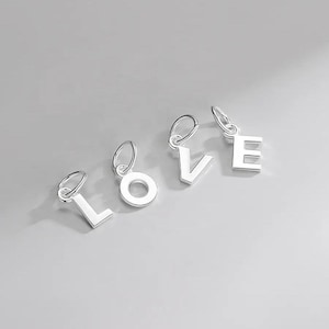 May include: Four silver charms spelling out the word "LOVE". Each charm is a letter of the alphabet and has a loop for attaching to a bracelet or necklace.
