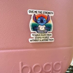 K&ouml;nnte beinhalten: Rosa Tragetasche mit dem Wort "bogg" auf der Vorderseite. Ein wei&szlig;er Aufkleber mit der Figur Stitch aus Lilo & Stitch ist auf der Tasche angebracht. Der Aufkleber lautet: "GIVE ME THE STRENGTH TO WALK AWAY FROM STUPID PEOPLE WITHOUT SLAPPING THEM."