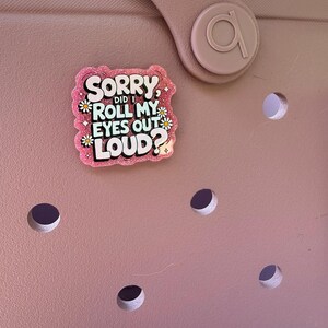 K&ouml;nnte beinhalten: Eine rosa Tasche mit einem dekorativen Anh&auml;nger mit der Aufschrift "Sorry, did I roll my eyes out loud?" in einer verspielten Schriftart. Der Anh&auml;nger ist rosa mit wei&szlig;em und schwarzem Text und kleinen G&auml;nsebl&uuml;mchen-Akzenten.