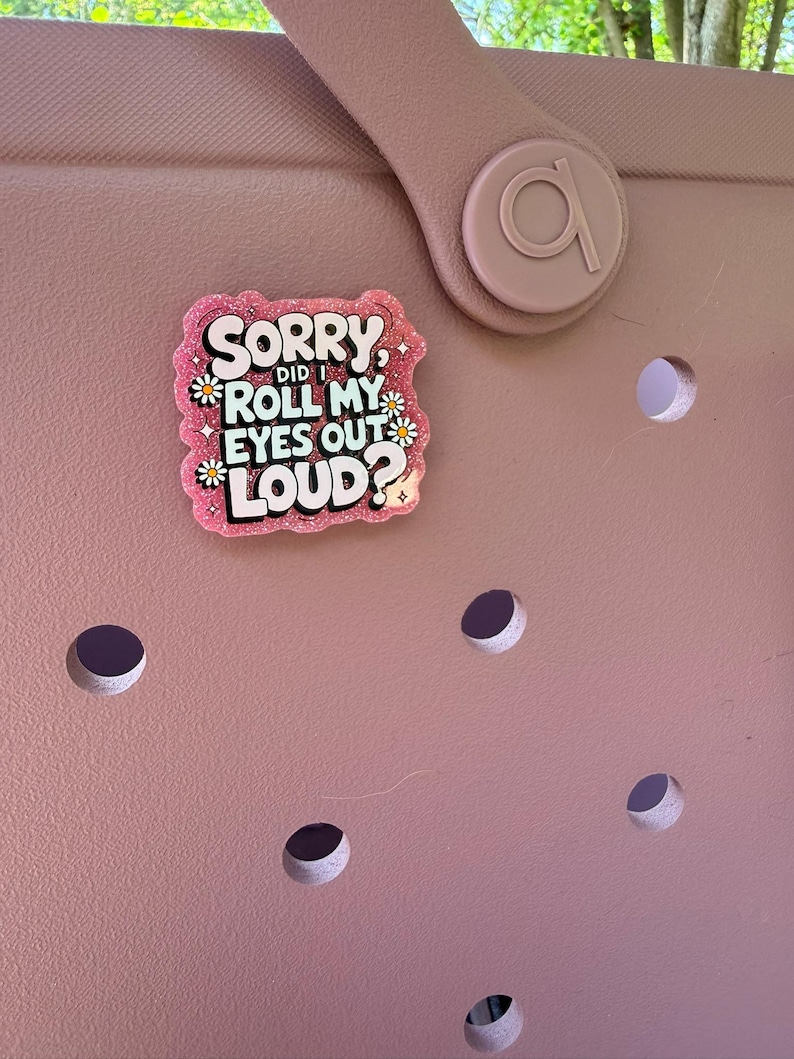 K&ouml;nnte beinhalten: Eine rosa Tasche mit einem dekorativen Anh&auml;nger mit der Aufschrift "Sorry, did I roll my eyes out loud?" in einer verspielten Schriftart. Der Anh&auml;nger ist rosa mit wei&szlig;em und schwarzem Text und kleinen G&auml;nsebl&uuml;mchen-Akzenten.