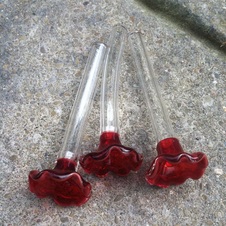 May include: Three clear glass hummingbird feeders with red glass flower-shaped bases.