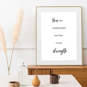 May include: A framed print with a white background and black text that reads "You are irreplaceable, and that is your strength."