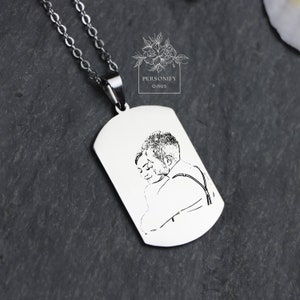 May include: A silver necklace with a dog tag pendant featuring a black and white line drawing of a couple embracing.