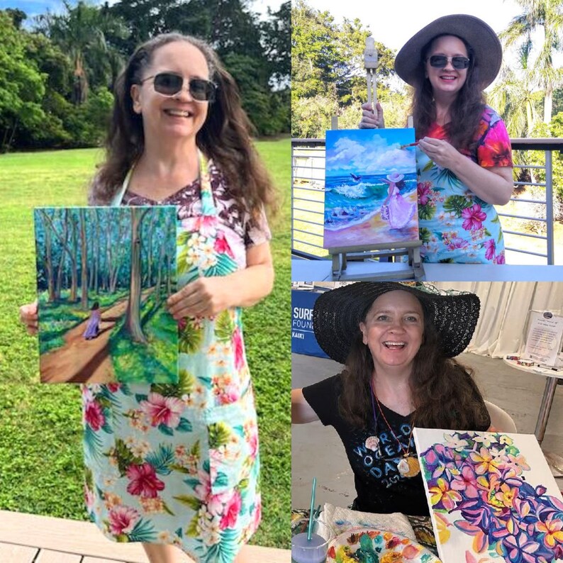 May include: A woman holding paintings of landscapes and seascapes. She is wearing a floral apron and sunglasses. The paintings depict a forest path, a beach scene with a figure, and a floral arrangement. The woman is smiling and appears to be an artist.