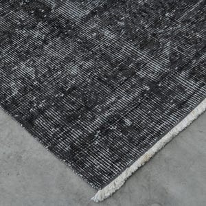 May include: Close-up of a black and white patterned rug with a white fringe border.