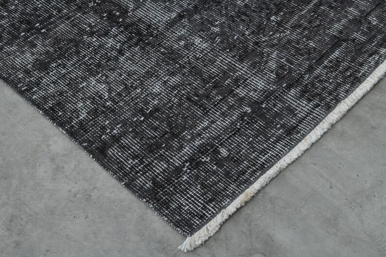 May include: Close-up of a black and white patterned rug with a white fringe border.