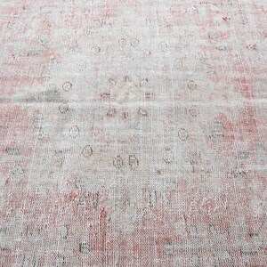May include: A vintage rug with a faded pink and white pattern. The rug has a distressed look with a worn and faded appearance.