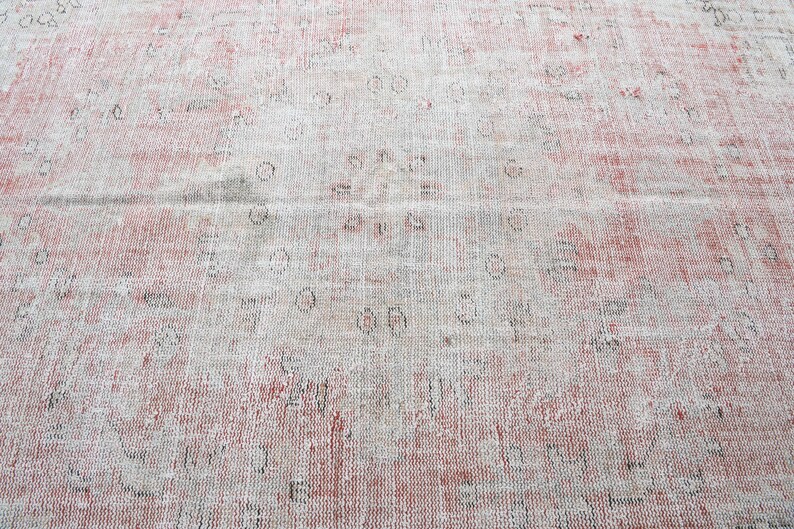 May include: A vintage rug with a faded pink and white pattern. The rug has a distressed look with a worn and faded appearance.