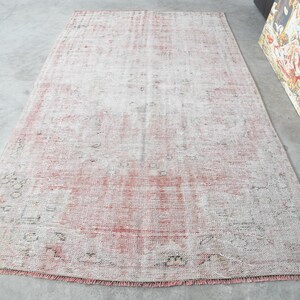 May include: A vintage-style rug with a faded pink and white pattern. The rug has a distressed look and is made of a soft, woven material.