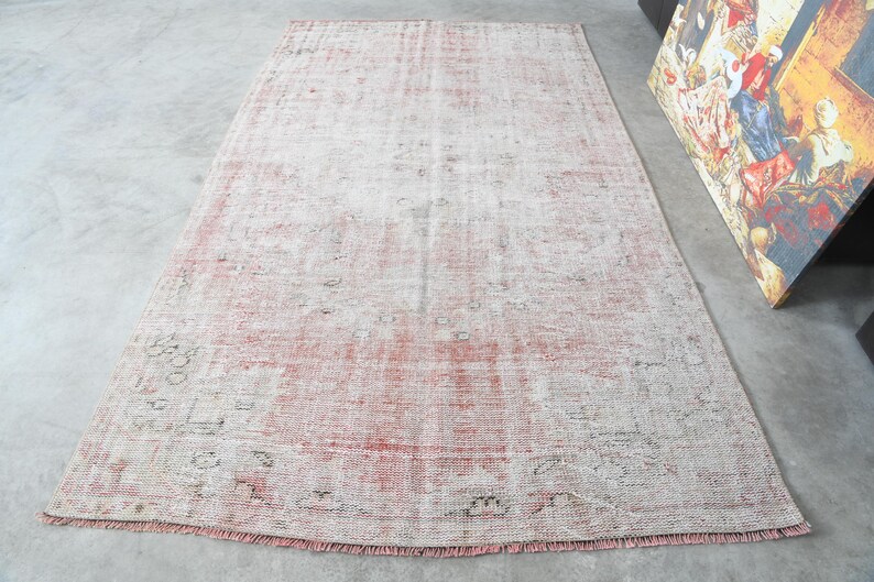 May include: A vintage-style rug with a faded pink and white pattern. The rug has a distressed look and is made of a soft, woven material.