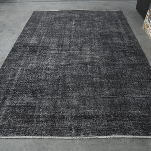May include: A dark gray area rug with a distressed, vintage look. The rug has a subtle pattern and a slightly textured surface.