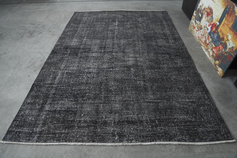 May include: A dark gray area rug with a distressed, vintage look. The rug has a subtle pattern and a slightly textured surface.