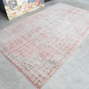 May include: A vintage rug with a faded pink and cream colour scheme. The rug has a distressed look with a subtle pattern throughout.