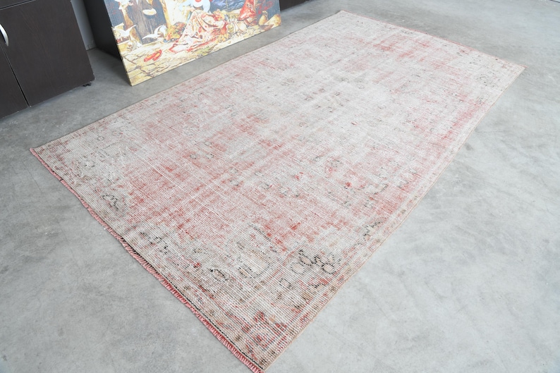 May include: A vintage rug with a faded pink and cream colour scheme. The rug has a distressed look with a subtle pattern throughout.