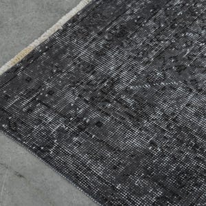 May include: A black and white patterned rug with a fringe edge. The rug has a distressed look and is made of a woven material.