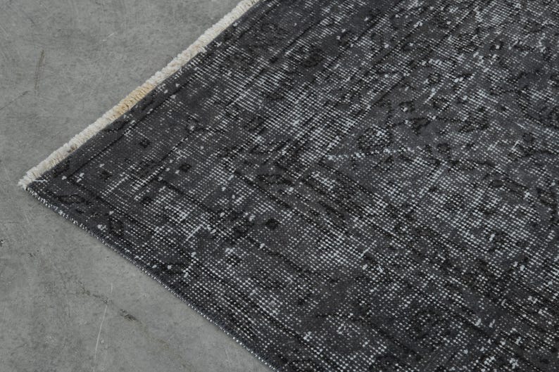 May include: A black and white patterned rug with a fringe edge. The rug has a distressed look and is made of a woven material.