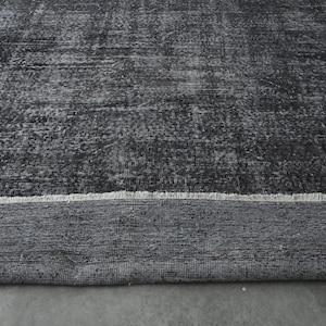 May include: A black and white rug with a distressed, vintage look. The rug has a fringe border and is made of a soft, woven material.