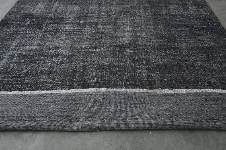 May include: A black and white rug with a distressed, vintage look. The rug has a fringe border and is made of a soft, woven material.