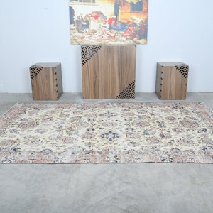 May include: A beige rug with a floral pattern and a dark blue border. Three wooden end tables with intricate cutouts are arranged on the rug.