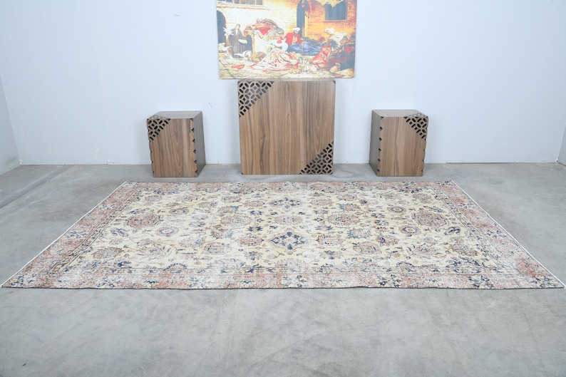 May include: A beige rug with a floral pattern and a dark blue border. Three wooden end tables with intricate cutouts are arranged on the rug.