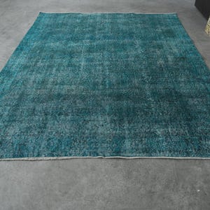 May include: A teal blue vintage rug with a distressed, faded look. The rug has a subtle pattern and a soft, worn texture.