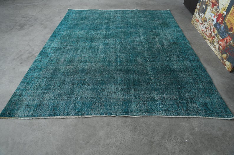 May include: A teal blue vintage rug with a distressed, faded look. The rug has a subtle pattern and a soft, worn texture.
